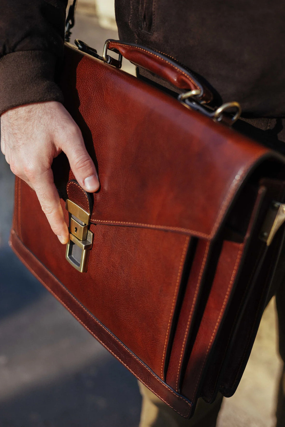 Close-up of a brass clasp and stitched flap on a leather briefcase