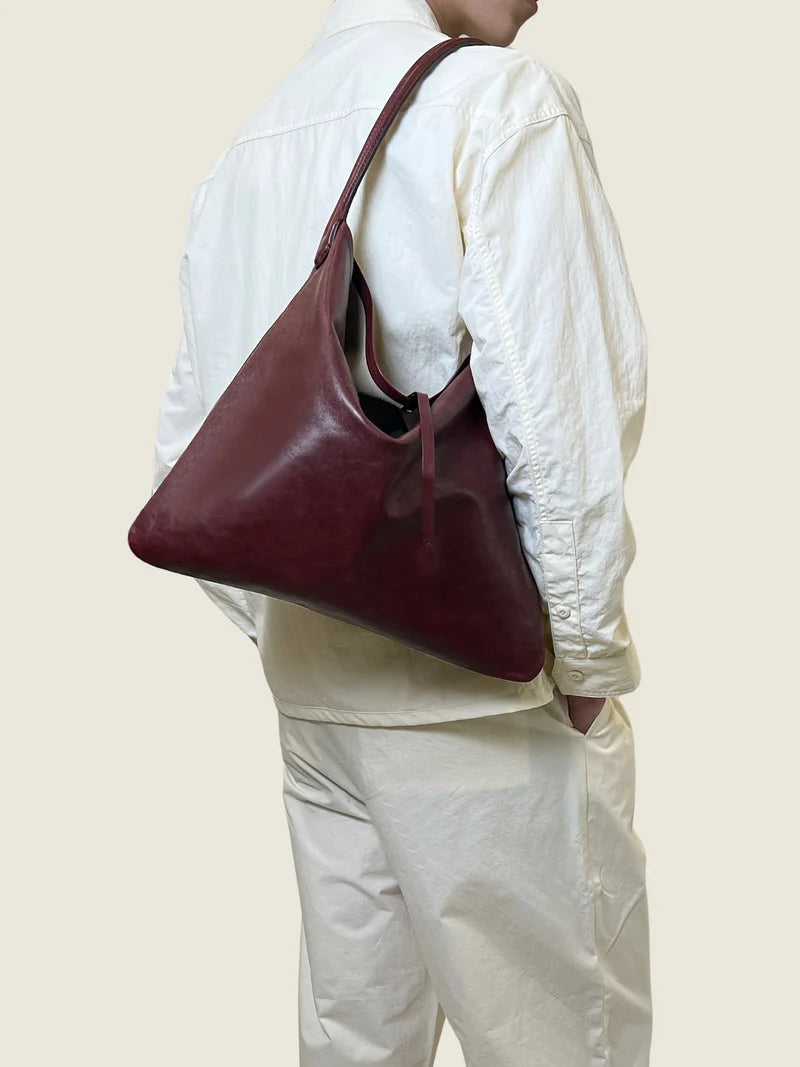 The burgundy leather tote worn on the shoulder, seen from behind