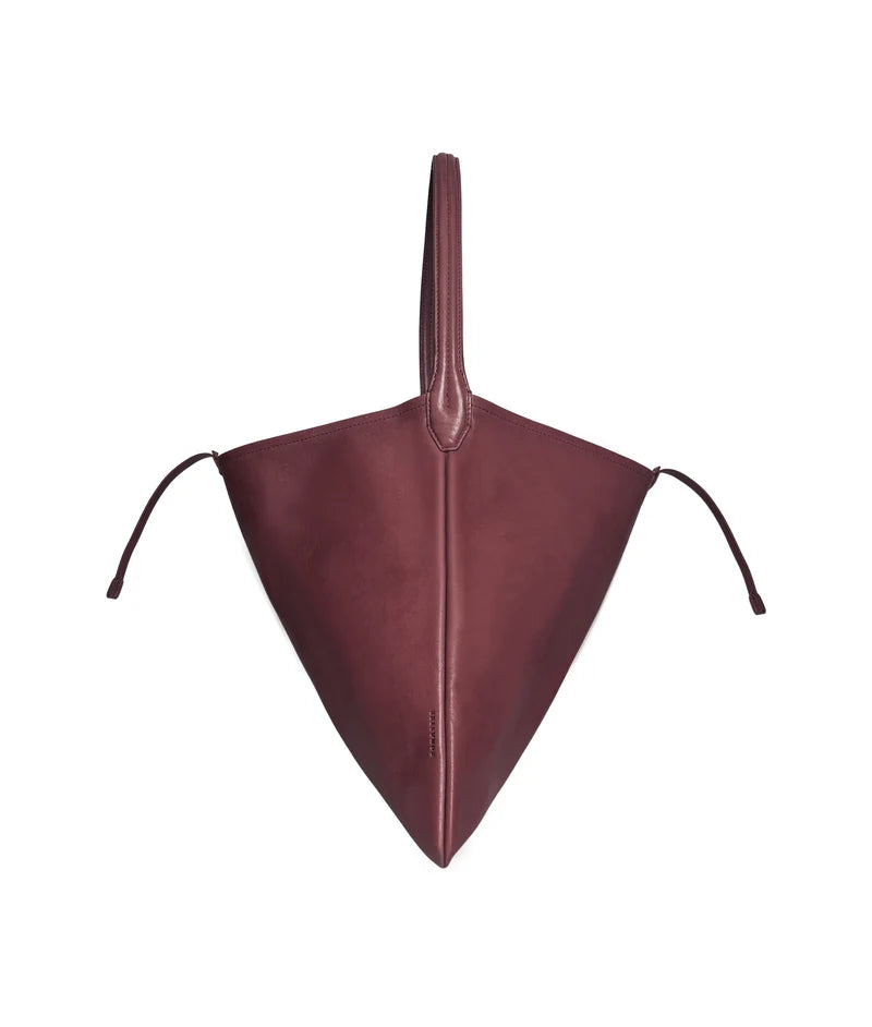 The burgundy tote laid flat, showing its triangular shape and leather ties