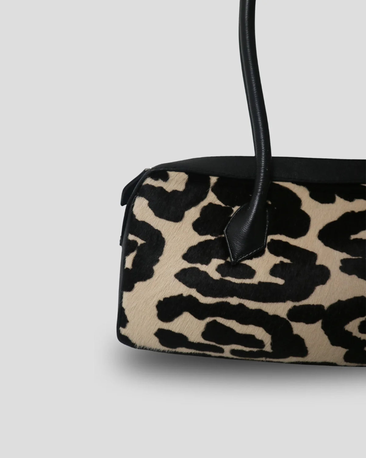 Close-up of the cow print and a top handle on the Cila bag