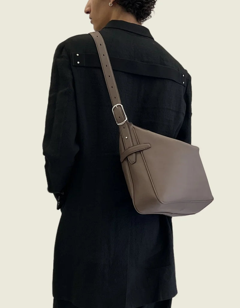 The taupe leather bag worn crossbody, seen from behind
