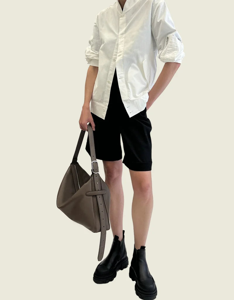 The taupe leather bag carried by its strap in one hand